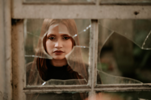 Woman looking through a broken glass door