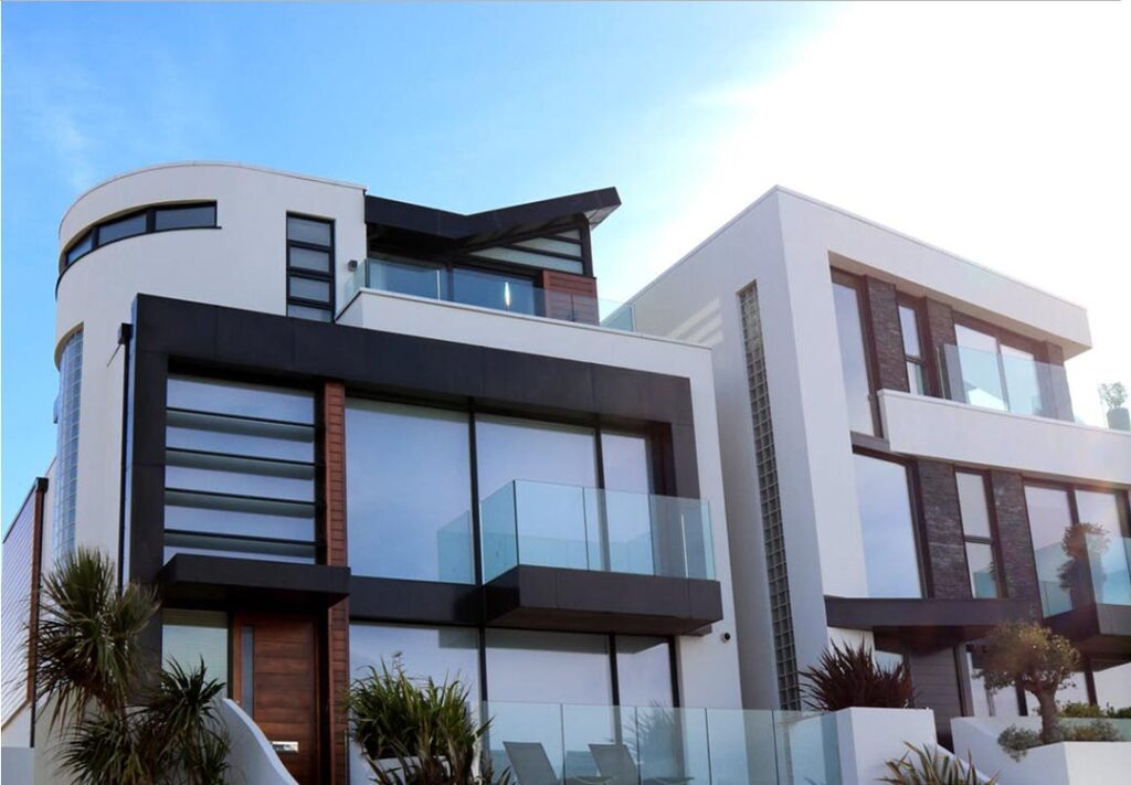Modern houses with large windows and glass balconies, showcasing sleek architectural design featuring patio doors with tempered glass for safety and style.